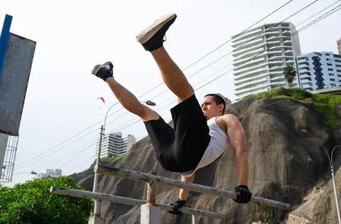 Handsome man exercising on parallel bars on the street outdoors. 写真素材