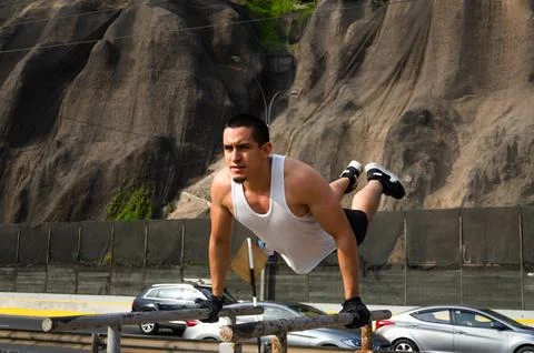 Handsome man exercising on parallel bars on the street outdoors. 写真素材