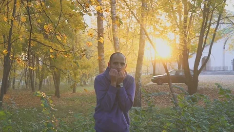 Handsome man feeling cold and warming hands, man freezes in the autumn park Video stock 96269953