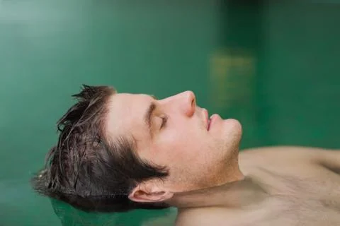 Handsome man floating in the pool Stock Photos