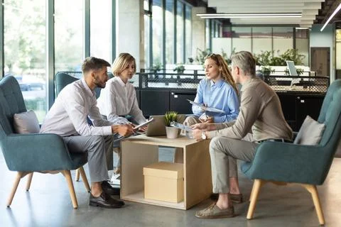 Handsome man gesturing and discussing something while his coworkers listening Stock Photos