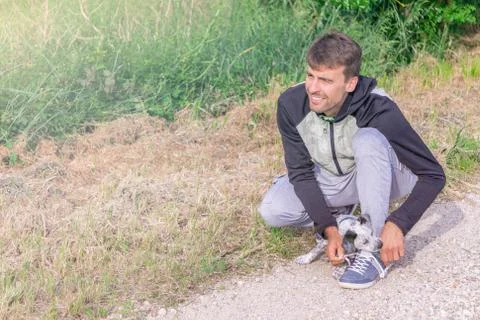 Handsome man getting ready to run and puppy helping to tie jogging shoes Stock Photos