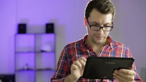 Handsome man with glasses talking on a fun video call on tablet and laughing. Stock Footage 70902974