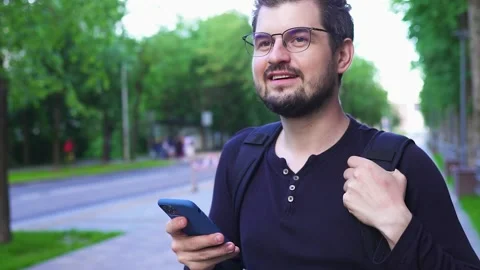 Handsome man in glasses using smartphone on the street Stock Footage 134697146