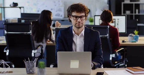 Handsome man in glasses working on the laptop in the big modern office space Stock Footage 82445627