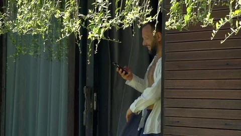Handsome man going outside and texting on smartphone, steadycam shot, slow motio Stock Footage 82451687