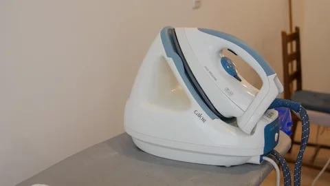 Handsome man hands using a domestic steam iron. Ironing is the use of a machine, Stock Footage 127373962