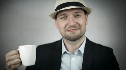 Handsome man in hat drinking coffee/isolated on grey background Stock Footage 39735462