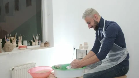 Handsome man having fun is moulding a ware in the pottery works studio Stock Footage 130875787