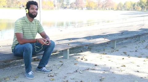 Handsome man with headphones listening to music on smartphone at park Stock Footage 59554969