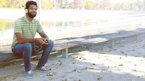 Handsome man with headphones listening to music on smartphone at park Stock Footage 59554972