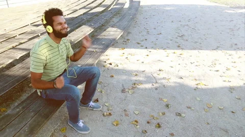Handsome man with headphones listening to music at park Stock Footage 59554986
