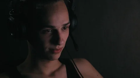 Handsome man in headpsones sitting in front of computer at home at night Stock Footage 99051089