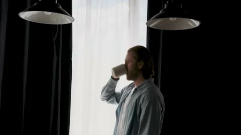 Handsome man in his 30s drinking coffee or tea near the window Stock Footage 202043975