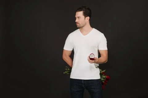 Handsome man holding proposal ring and bouquet with red roses on grey background 스톡 사진