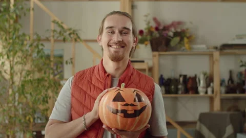 A handsome man is holding a pumpkin and looking to the camera Stock Footage 170270441