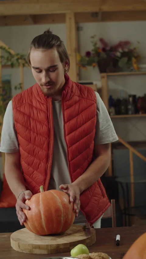 A handsome man is holding a pumpkin and looking to the camera Stock Footage 170465443