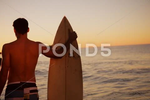 Handsome man holding a surfboard Stock Photos