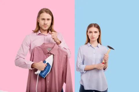 Handsome man ironing clothes while woman holding hammer Stock Photos