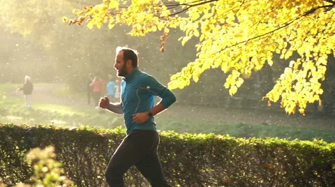 Handsome man jogging in park during autumn, slow motion shot at 240fps Stock Footage 56290197