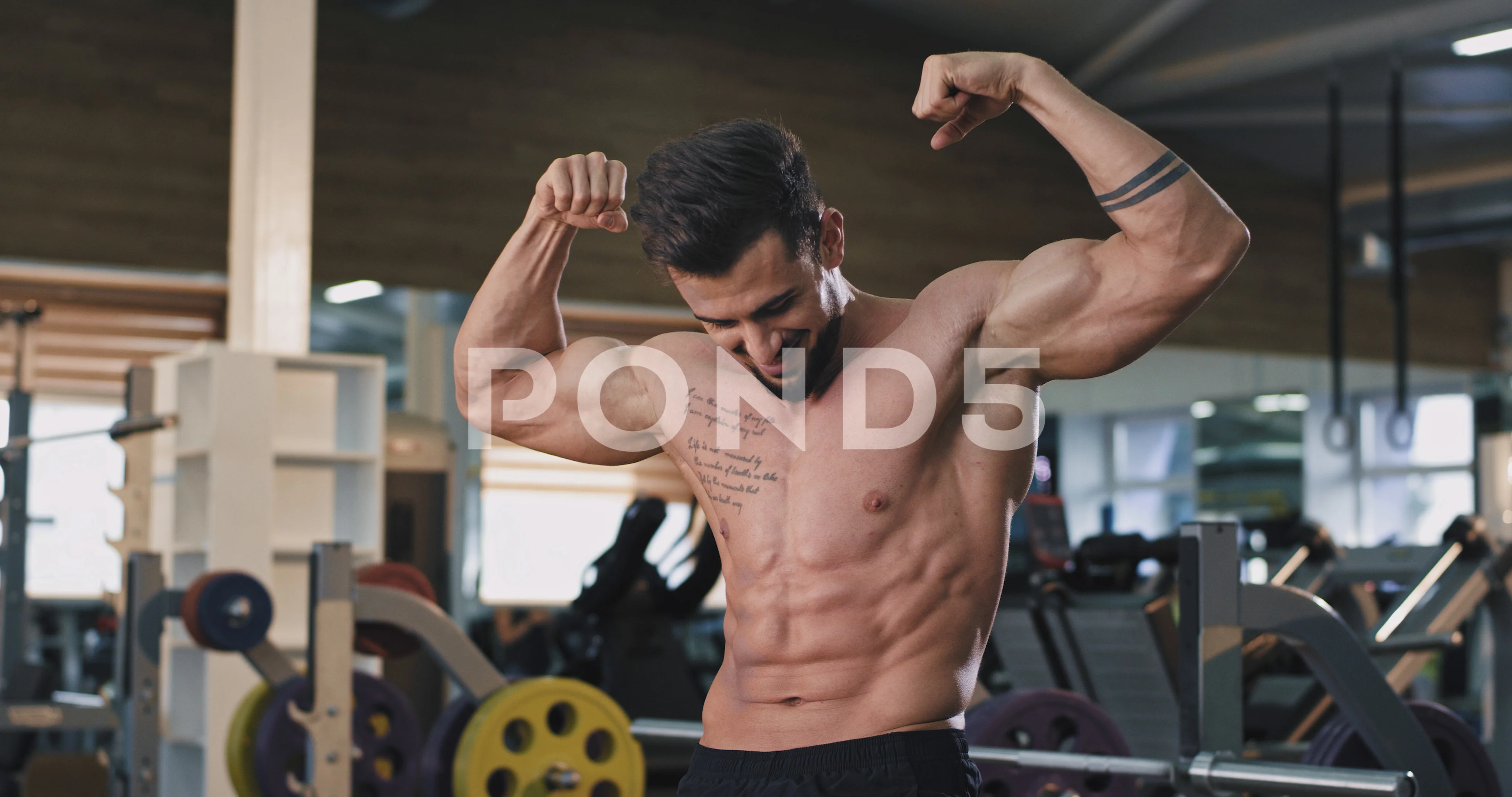 Fotografia do Stock: Fitness in gym, sport and healthy lifestyle concept.  Handsome athletic man with naked torso demonstrates his muscles and trained  body. Bodybuilder male model posing on grey background.