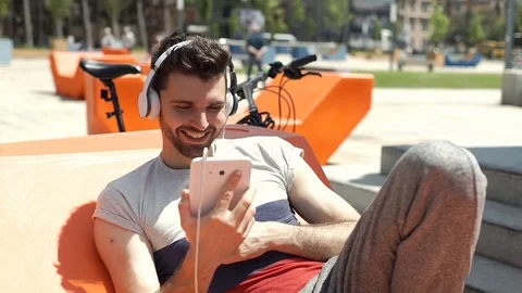 Handsome man laughing while watching something on tablet in the city, steadycam  動画素材 77032993