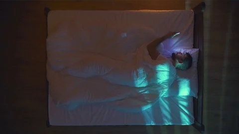 The handsome man lay on the bed and phone. Evening night time. View from above Stock Footage 71964765