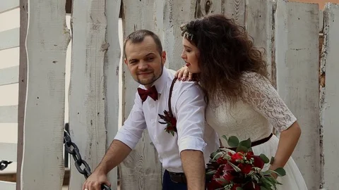 A handsome man leaned on an iron chain. Young beautiful woman hugging him. In Stock Footage 69888357