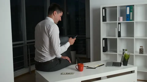 Handsome man linger at work until late at night sitting at desk in office with Stockbeeldmateriaal 133573395