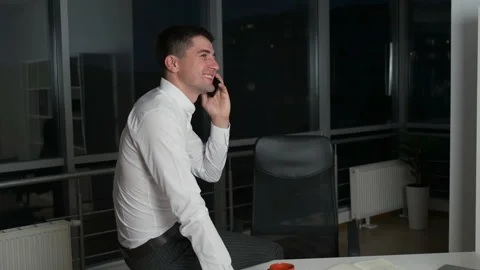 Handsome man linger at work until late at night sitting at desk in office with Stock Footage 134044240