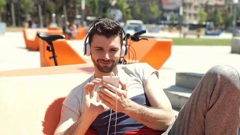 Handsome man listening music and browsing internet on smartphone, steadycam shot Stock Footage