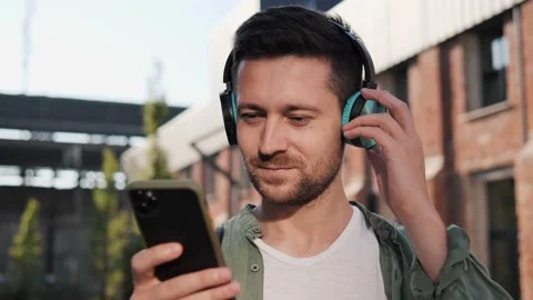 Handsome man listening to music using mobile phone app outdoors on empty street. Stock-Footage 214863191