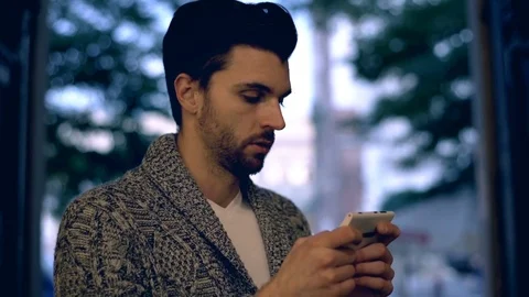 Handsome man looking absorbed while typing message on smartphone Stock-Footage 70126345