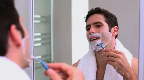 Handsome man looking at mirror and shaving Stock Footage 32879281