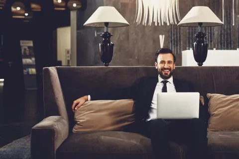 Handsome man looking relaxed and sitting on the sofa with laptop Stock Photos