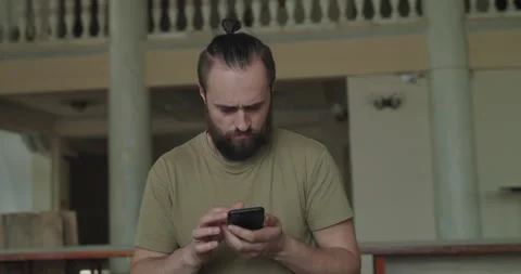 Handsome man looking seriously when using mobile phone in a room Video stock 130814401