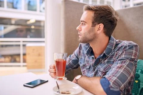 Handsome man looking sideways while holding his tea in cafe Foto stock