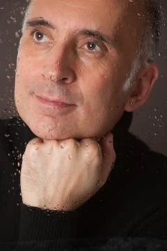 Handsome man looking through a wet window Stock Photos