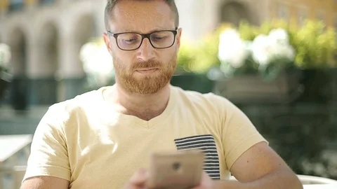 Handsome man looks absorbed while texting messages on smartphone in the cafe, st 動画素材 76986179