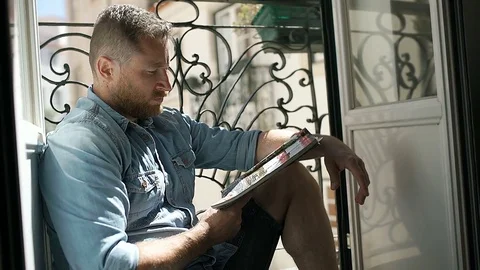 Handsome man looks absorbed while reading newspaper, steadycam shot Stock Footage