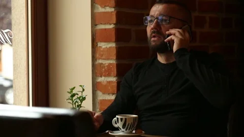 Handsome man looks angry while speaking with someone on cellphone Stock Footage 80424282