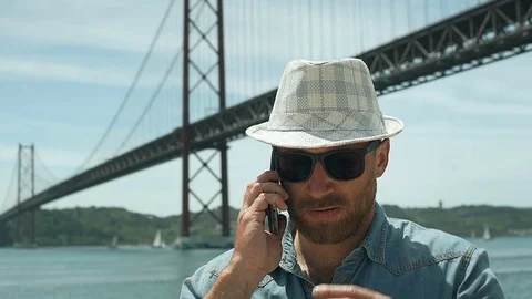 Handsome man looks dissatisfied while speaking on cellphone, steadycam shot Stock Footage 76991040