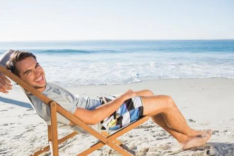 Handsome man lying on his deck chair smiling at camera Stock Photos