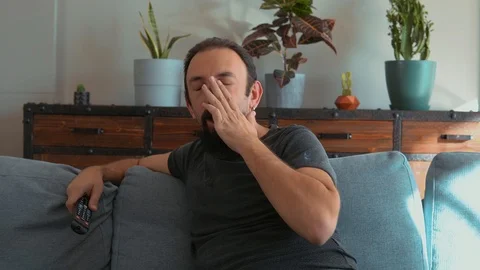 Handsome man lying on the sofa and watching TV Stock Footage 121579702