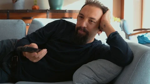 Handsome man lying on the sofa and watching TV Stock Footage 121580691