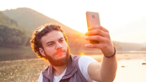 A handsome man makes a photo in the background of the sunset 動画素材 81577564