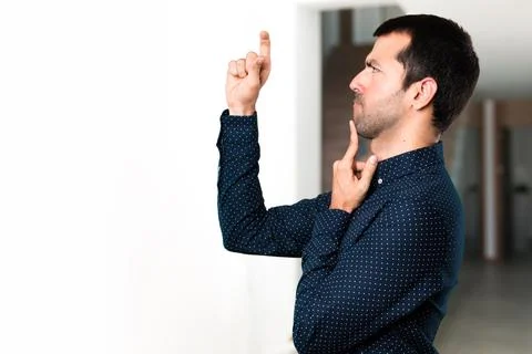 Handsome man making tiny sign inside house Stock Photos