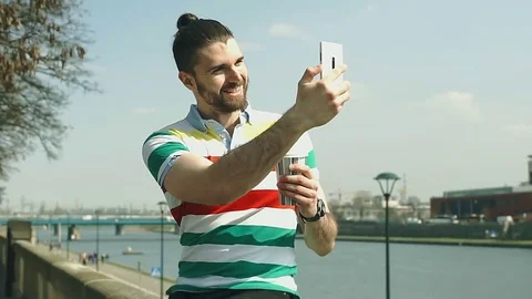 Handsome man with mud bun doing selfies on smartphone while standing next to the Stock-Footage 74412231