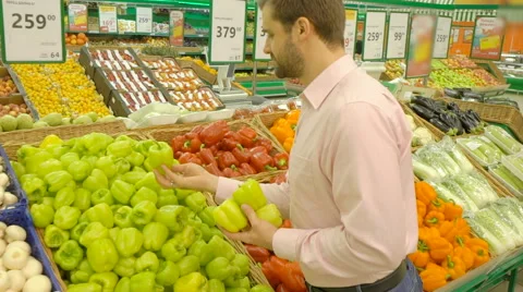 Handsome man picking up green bell peppers Stock Footage 63432187