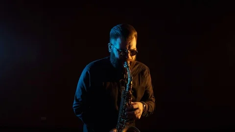 Handsome man playing the saxophone, black background, isolated, solo Stock Footage 127054352
